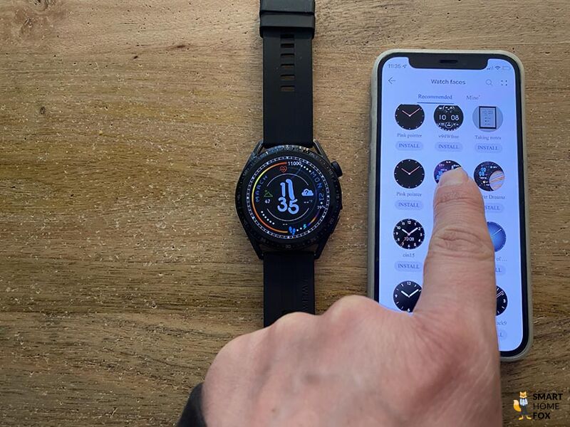 Man sieht die Huawei Watch GT 3 neben einem iPhone auf dem Tisch.